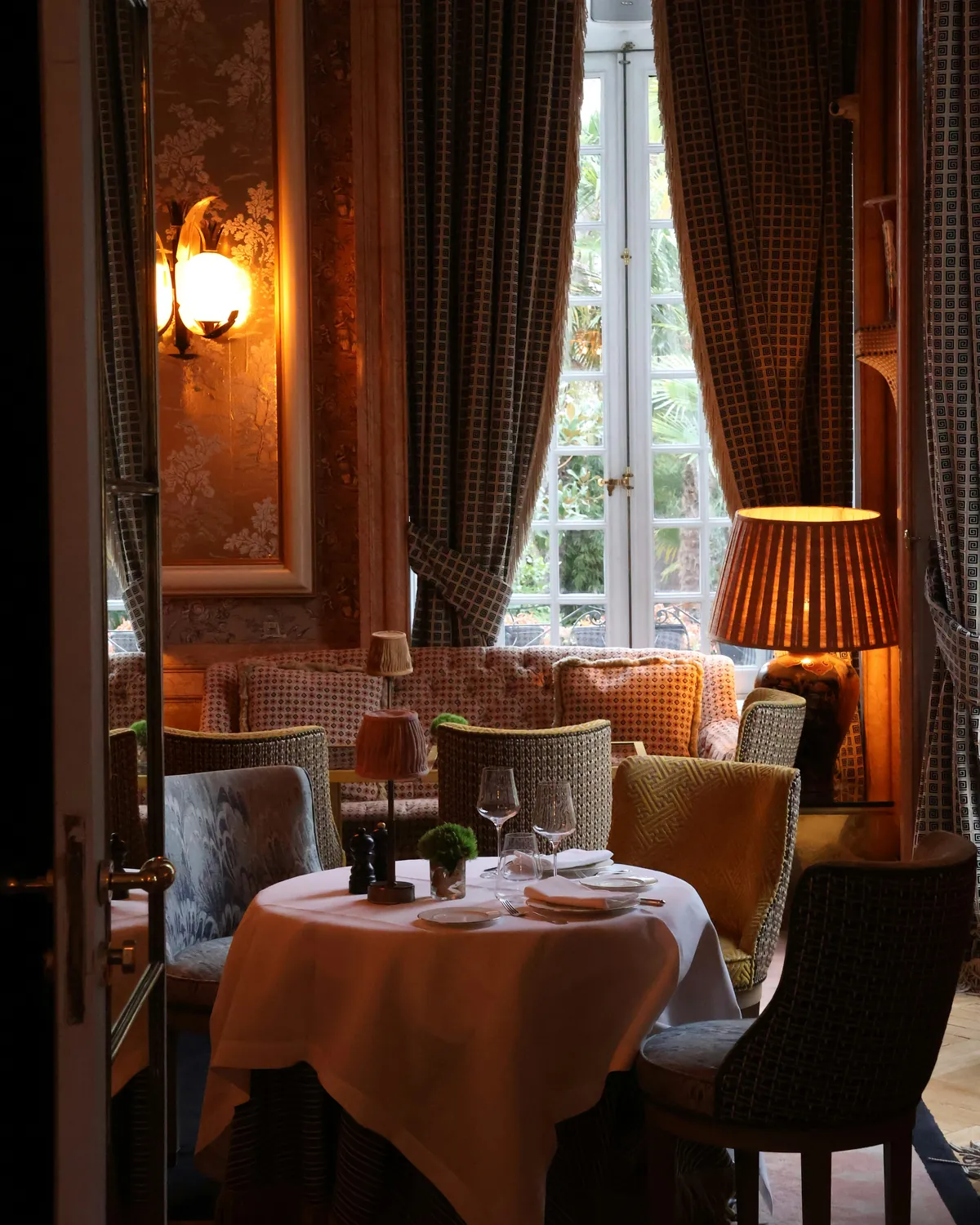 Gün ışığı ve sıcak lambalarla aydınlanan, kurulu masalı şık bir restoran salonu